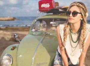 Autoimmune Issues: Woman sitting on hood of a green VW on the beach