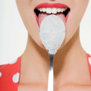 THE IMPACT OF DIET ON SKIN MIC ROBIOME HEALTH: WOMAN LICKING A SPOON WITH SUGAR