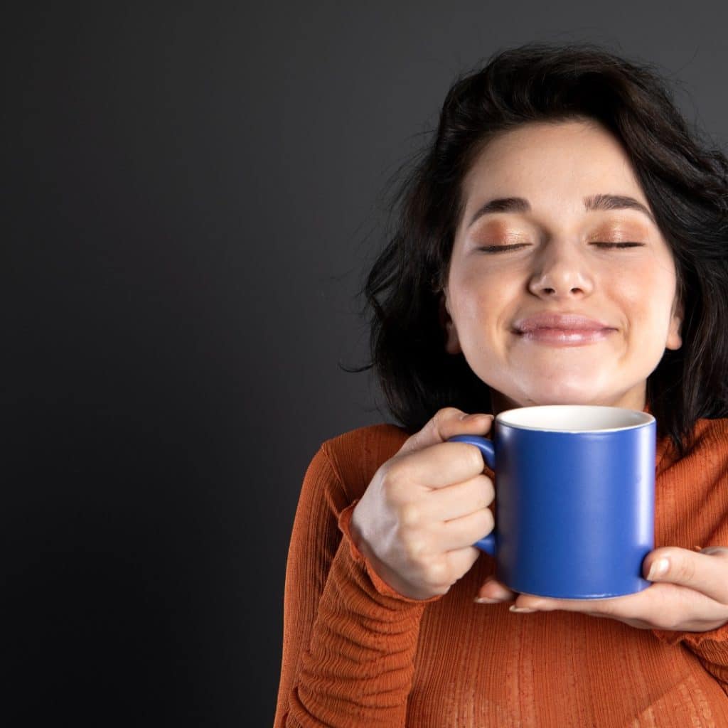 better caffeine choices: woman smiling and holding a blue cup of coffee