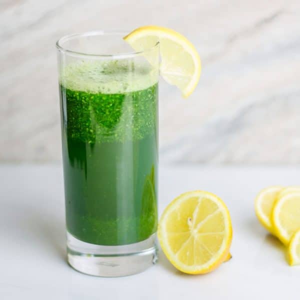 JUICING WITHOUT A JUICER: GREEN JUICE WITH LEMONS ON A WHITE TABLE