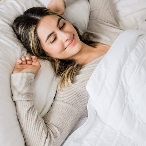 TOP BEDTIME SNACKS FOR A GOOD NIGHT'S SLEEP: WOMAN WITH A SMILE ON HER FACE GETTING A GOOD NIGHT'S SLEEP